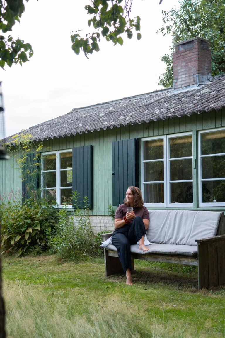 een vrouw geniet van thee voor een natuurhuisje tijdens een weekend alleen weg